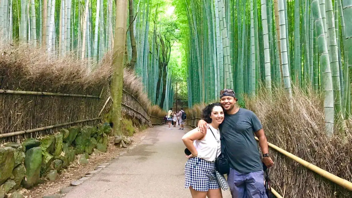 Private guide leading two travelers along a quiet stretch of the Sagano Bamboo Forest path in the Sagano district of Kyoto